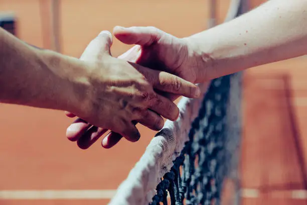 Handshake between two people on the tennis field over the net