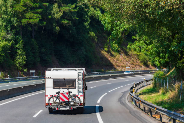 istock Motorhome with a bicycle behind driving on a highway surrounded by trees 1413380842