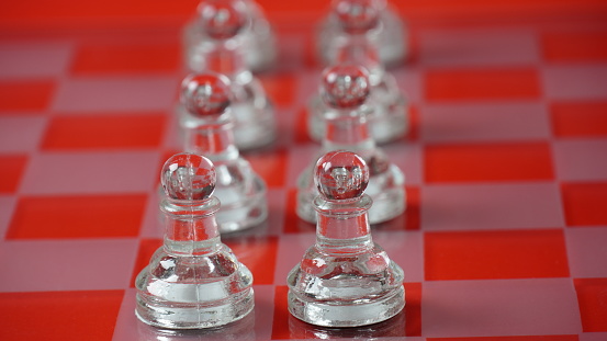 Pieces of transparent chess,  pawns. Transparent chess figures on chessboard, red tone.