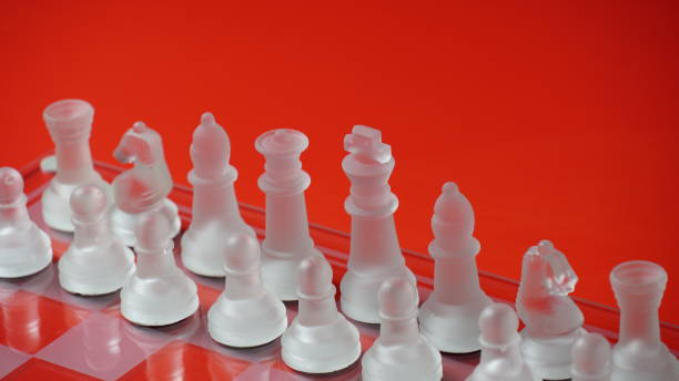 istock Transparent chess figures, on starting position, on reflective chess board, red tone. Strategic Chess board game 1413381744