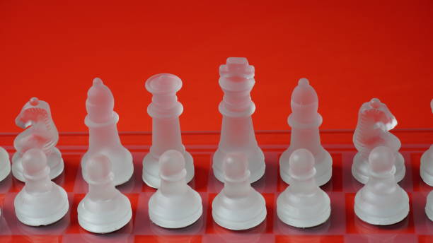 istock Transparent chess figures, on starting position, on reflective chess board, red tone. Strategic Chess board game 1413381753