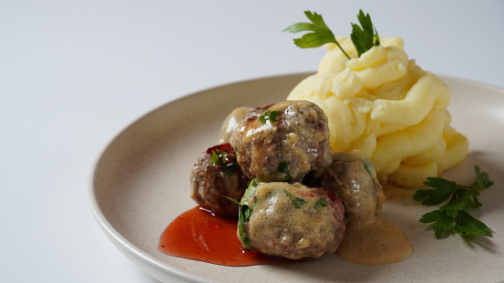 A plate of Swedish meatballs with mashed potatoes, traditional creamy gravy, and lingonberry.