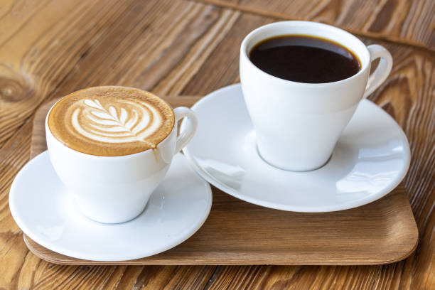 istock Flat white or cappuccino and filter coffee in white cups on wooden table. Different coffee styles, morning drink in cafe on small wooden tray 1413383975