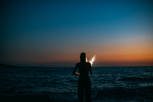 Young Woman Holding Sparkler by the Sea