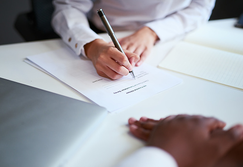 Signing a contract or agreement for an investment at a business meeting. Closeup of hands filling in a form or legal settlement for a financial partnership inside an office by a sales employee