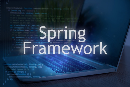 Spring framework inscription against laptop and code background. Technology concept.