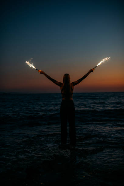 istock Young Woman Burning Sparkler at Sunset 1413394507
