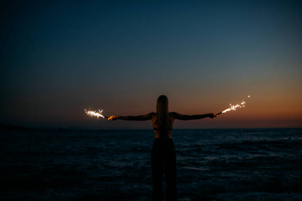 istock Young Woman Burning Sparkler at Sunset 1413394515