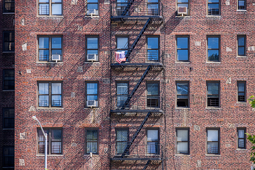 Northern Broadway, Manhattan, New York, NY, USA - June 28, 2022: Façade of a brown stone building with fire escape on a sunny day