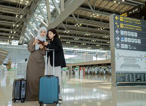 Two businesswomen arriving at the airport checking documents for travel in the airport terminal.
