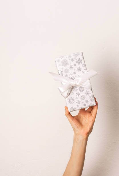 istock Man's hand holding a gift box with a bow 1413396823