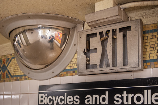 5th Avenue Subway Station, Manhattan, New York, NY, USA - June 29, 2022: Mirror (with the reflection of the photographer) and exit sign in the subway
