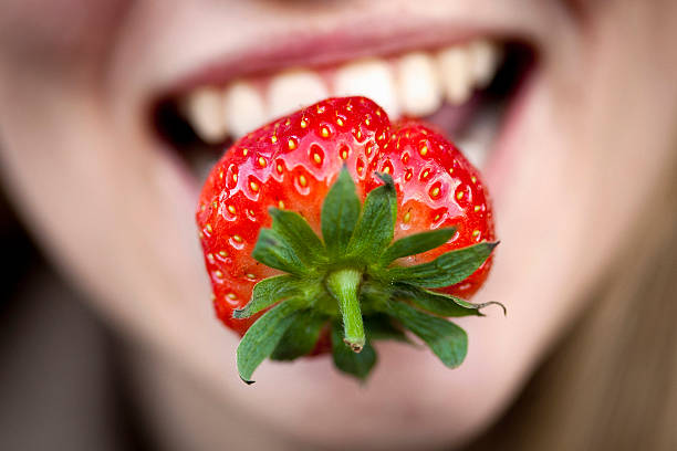 nahaufnahme des strawberry in womans mund - strawberry fruit single object food stock-fotos und bilder