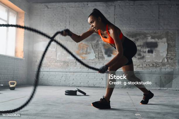 Concentrated Young African Woman Exercising With Battle Ropes In Gym Stock Photo - Download Image Now