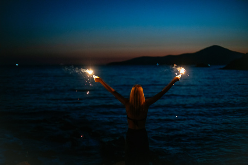 Young Woman Holding Sparkler by the Sea
