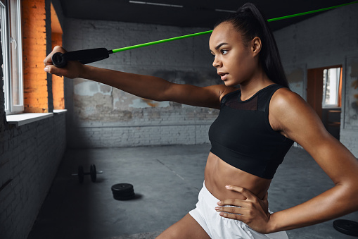 Confident young woman exercising with elastic resistance band in gym