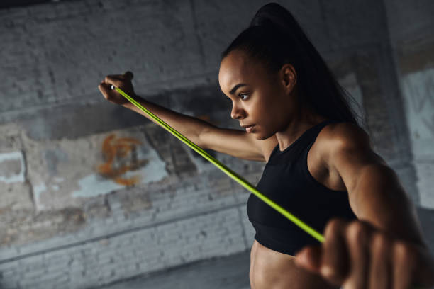 istock Concentrated young African woman using rope while doing stretching exercises in gym 1413402927