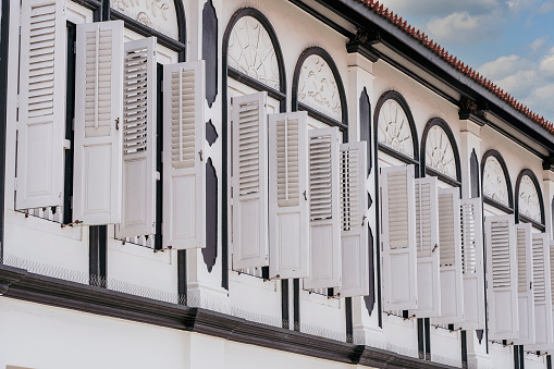 Window with white wooden shutters on wall building on the street in Singapore