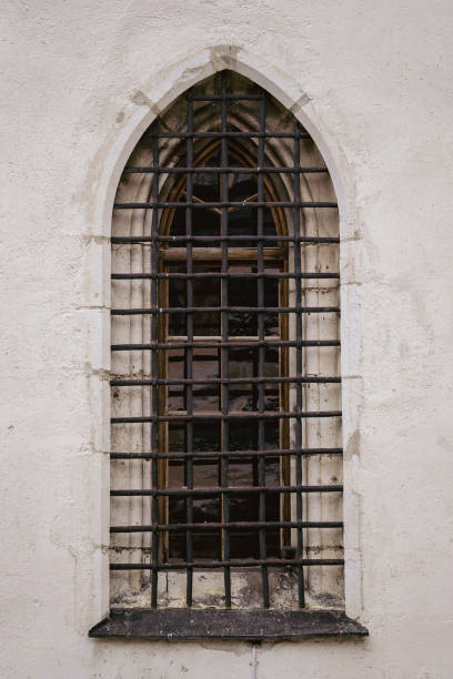 alte weiße steinmauer mit einem gewölbten gitterfenster auf der straße, österreich - prison architecture black white stock-fotos und bilder