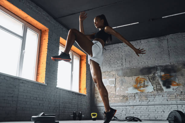 istock Confident young African woman jumping while exercising in gym 1413404059