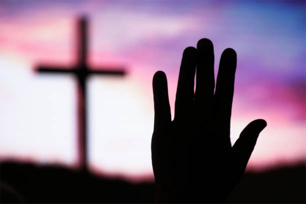 Hand raising, blurred christian cross background stock photo