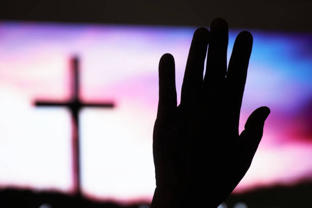 istock Hand raising, blurred christian cross background 1413406853
