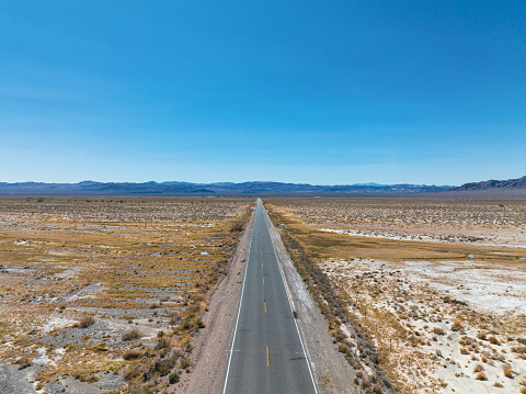 Cars driving on a straight open highway through desert landscape near Las Vegas in Nevada, USA.