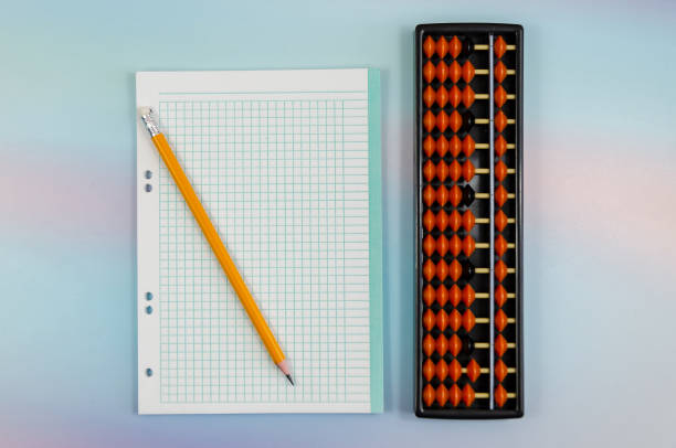 istock Notebook sheet in cage, pencil and an abacus for mental arithmetic on colored background 1413409406
