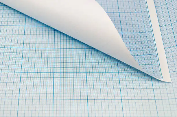 Blank unfolded sheet and roll of graph paper. Background for sketching, painting, drawing. Roll of blue graph paper on sheet of graph paper.