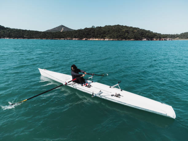 A woman single rowing in the sea.
