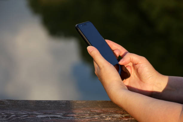 istock Female hands with smartphone close up on lake background 1413413808