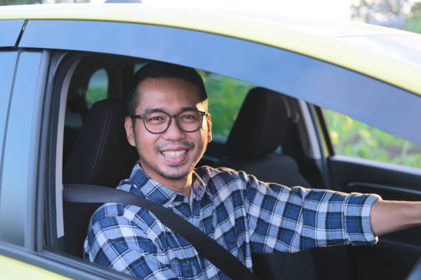 istock Asian man smiling to camera while driving his car 1413414880