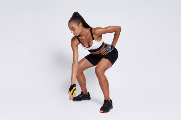 istock Confident African woman warming up while standing in squatting position against white background 1413416276