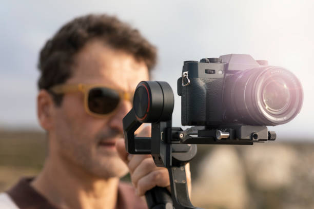 istock 3-axis outdoor vlogger gimbal recording content digital camera stabilizer gimbal. Man with camera in hand documenting trip for archival video. Videographer concept with gimbal in hand. selective focus 1413416670