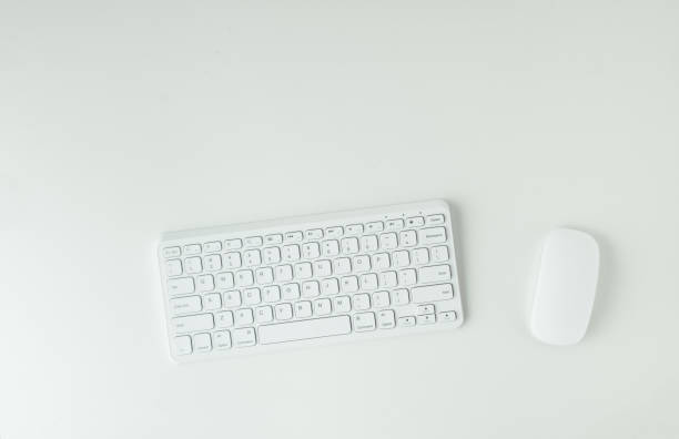 istock White GWERTY keyboard and mouse on the white table surface. Working place concept. Flat lay of office desk. Copy space for a text 1413416745