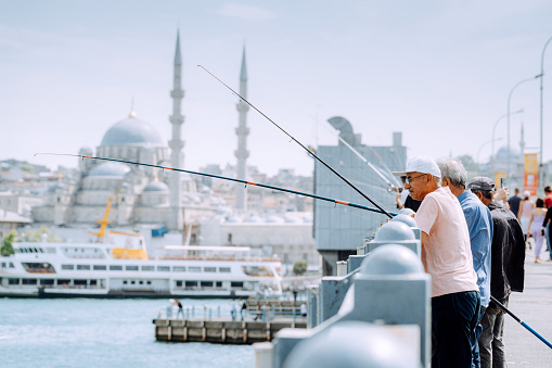 Istanbul, Turkey - 06 June, 2022: People fishing from the Galata Bridge in Istanbul, Turkey.