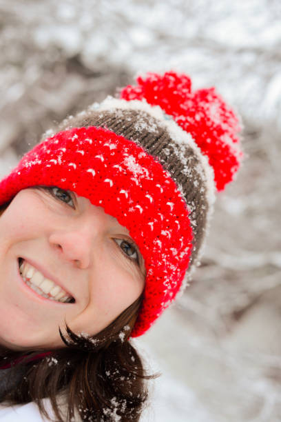 Happy smiling young woman wearing a woolly red bobble hat with snowflakes on it in Lapland, happy to be meeting Santa in a few day. stock photo