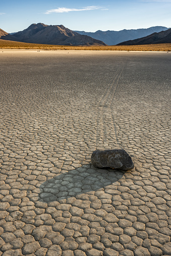 Shadows Pass Over The Racetrack Playa With The Back Mountains in Golden Light in Death Valley