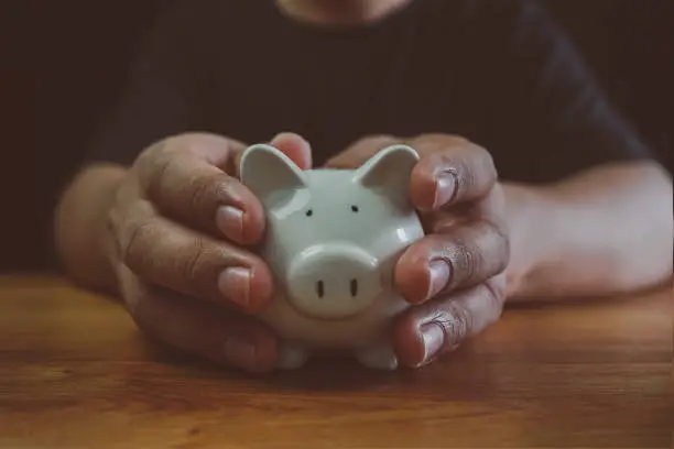 Man hand holding piggy bank on wood table. Save money and financial investment, Saving energy and money concept. idea for save or investment, The concept of saving money or savings, investment.
