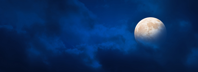 beautiful shiny full moon at cloudy night sky, dark blue background banner with copy space