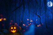 ブルームーンハロウィンの夜の幽霊の森、つまみの木の間に幽霊のような不気味な光が灯るジャック・オ・ランタン、コピースペース付きの招待状コンセプト