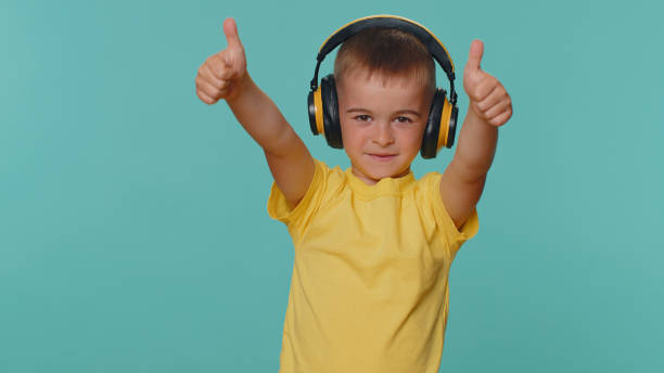 niños pequeños felices escuchando música a través de auriculares, bailando discoteca, engañando, divirtiéndose - headphones party little boys dancing fotografías e imágenes de stock