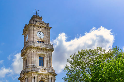 Istanbul, Turkey - May 1, 2022. Ancient clock tower in Dolmabahce Palace against a blue sky with clouds