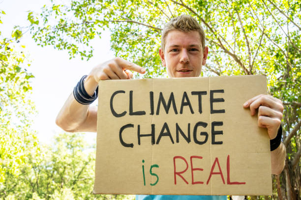 istock Protester holding sign Stop Climate Change. Man with placard at protest rally demonstration, strike against global warming. 1413432254