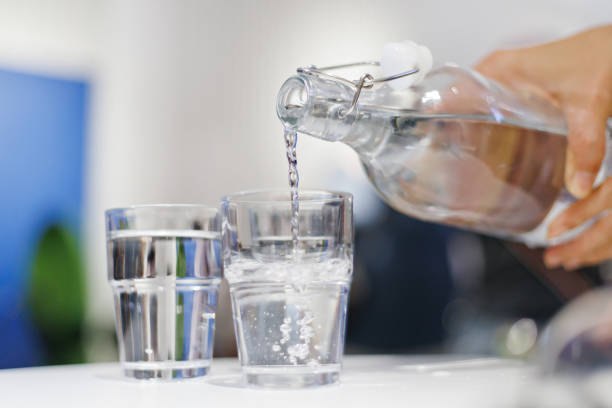 istock Pouring water from bottle into the glass in a restaurant. 1413433073