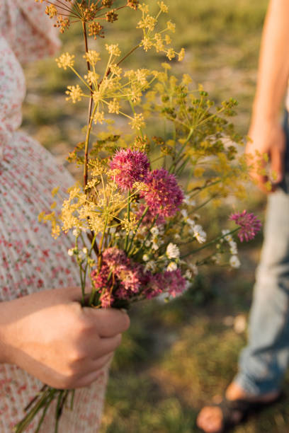 fleurs sauvages vivantes sur le fond du ventre de la femme enceinte. mise au point sélective. photo pour des articles sur la grossesse, la santé, les femmes. - kit mains libres photos et images de collection