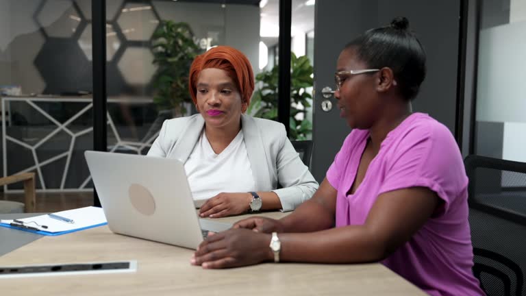 Side view mixed race businesswoman meeting with African woman in glass boardroom