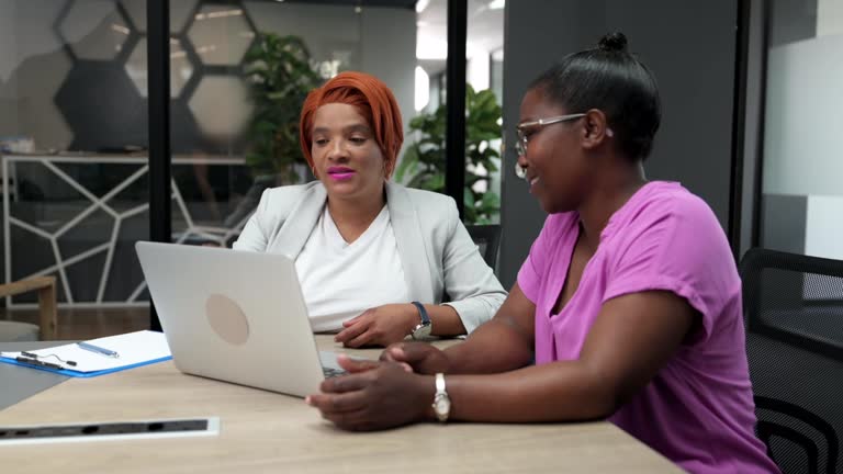 Side view mixed race businesswoman meeting with African woman in glass boardroom