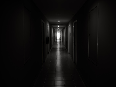 Dark mysterious corridor in building. Door room perspective in lonely quiet building with walkway heading to the light at the end of the way, black and white style. hope, brave and fear concept.