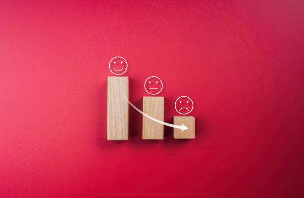 istock Feedback, client survey, customer experience satisfaction rating with emoticon face. Rising arrow down on sad face appear on wooden cube blocks stacks on the growth chart steps on red background. 1413438757